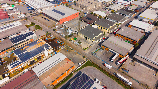 Aerial view of an industrial zone featuring warehouses with solar panels parked trucks and power lines in Milan Lombardy Italy.