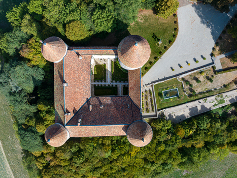 Aerial view of Champvent Castle with its four corner towers terracotta tiled roof and central courtyard surrounded by lush trees and manicured gardens in Champvent Vaud Switzerland. Aerial view of Champvent Castle with its four corner towers terracotta tiled roof and central courtyard surrounded by lush trees and manicured gardens in Champvent Vaud Switzerland.