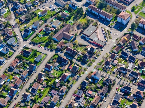 Aerial view of houses with red rooftops and lush green gardens neatly aligned streets and buildings form a vibrant urban tapestry Sausheim Grand Est France.