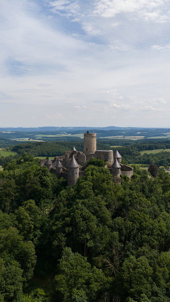 Aerial view of Nurburg Castle surrounded by lush green forests and rolling hills in Nurburg Rhineland Palatinate Germany. Aerial view of Nurburg Castle surrounded by lush green forests and rolling hills in Nurburg Rhineland Palatinate Germany.