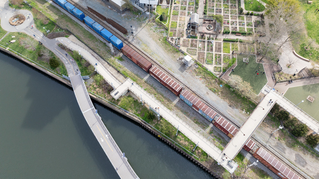 Aerial view of a train snaking along the riverbank with a pedestrian bridge arching gracefully over the water Harrisburg Pennsylvania United States. Aerial view of a train snaking along the riverbank with a pedestrian bridge arching gracefully over the water Harrisburg Pennsylvania United States.