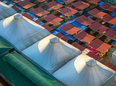 Aerial view of a market featuring large white conical tent roofs and rows of red roofed stalls under bright sunlight in Belgrade City of Belgrade Serbia. Aerial view of a market featuring large white conical tent roofs and rows of red roofed stalls under bright sunlight in Belgrade City of Belgrade Serbia.