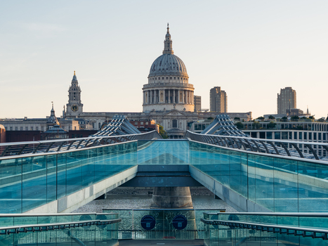 London United Kingdom 21 June 2025 View of St. Paul s Cathedral dome rising majestically behind the modern glass paneled walkway bathed in the soft glow of the evening sun. London United Kingdom 21 June 2025 View of St. Paul s Cathedral dome rising majestically behind the modern glass paneled walkway bathed in the soft glow of the evening sun.