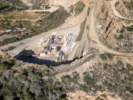 Aerial view of an industrial quarry site with processing machinery conveyor belts and dirt roads carved into the rocky landscape in Teulada Valencian Community Spain.
