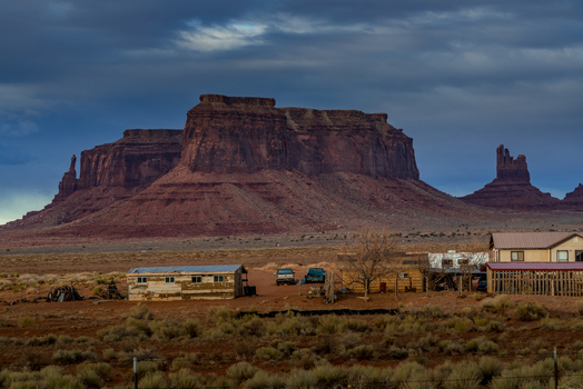 View of Monument Valley Tribal Park with its iconic red sandstone buttes rising above the desert landscape and small residential buildings in Oljato Monument Valley Utah United States.