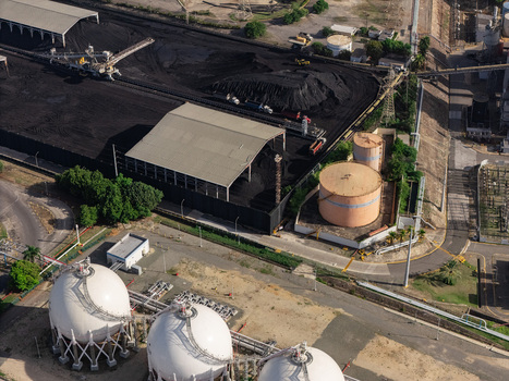 Aerial view of industrial facility featuring large spherical storage tanks a covered coal storage area and infrastructure in Bajos de Haina San Cristobal Province Dominican Republic.