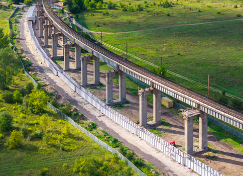 Aerial view of the elevated railway viaduct spanning across the green landscape with concrete pillars and metal tracks in Poznan Greater Poland Voivod Poland. Aerial view of the elevated railway viaduct spanning across the green landscape with concrete pillars and metal tracks in Poznan Greater Poland Voivod Poland.