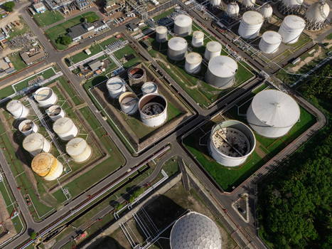 Aerial view of an industrial oil refinery with numerous large white storage tanks pipelines and paved roads in Bajos de Haina San Cristobal Provinc Dominican Republic.