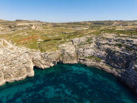 Aerial view of Dwejra Bay featuring turquoise waters rugged limestone cliffs and green terraced fields Gozo Region Malta. Aerial view of Dwejra Bay featuring turquoise waters rugged limestone cliffs and green terraced fields Gozo Region Malta.
