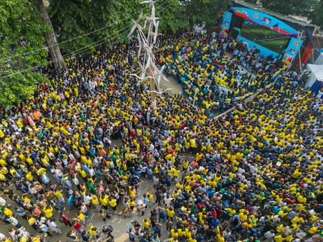 Dhaka Bangladesh 20 June 2026 Aerial view of a large crowd in yellow shirts gathered at Dhaka University Campus for an event with a central sculpture screen and trees. Dhaka Bangladesh 20 June 2026 Aerial view of a large crowd in yellow shirts gathered at Dhaka University Campus for an event with a central sculpture screen and trees.