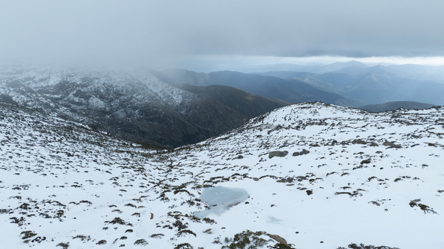 Aerial view of the snow covered Glacial Valley of Zezere with rocky slopes and thick fog over the mountain peaks in Manteigas Guarda District Portugal. Aerial view of the snow covered Glacial Valley of Zezere with rocky slopes and thick fog over the mountain peaks in Manteigas Guarda District Portugal.