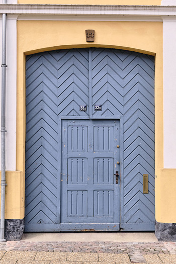 Viborg Denmark 07 August 2026 View of a blue chevron patterned wooden door with house numbers 33A and 33B set in a yellow historic building in the old town of Viborg.