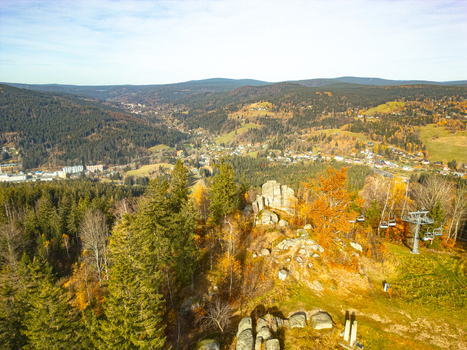 Aerial view of the rocky outcrops and autumn forest surrounding the Tanvaldsky Spicak ski resort with a chairlift and the town of Tanvald Tanvald Liberecky kraj Czechia.