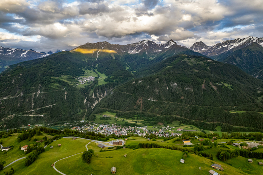 Aerial view of the village of Prutz nestled in the lush green valley of the Tyrolean Alps surrounded by towering mountains under a dramatic cloudy sky Prutz Tyrol Austria. Aerial view of the village of Prutz nestled in the lush green valley of the Tyrolean Alps surrounded by towering mountains under a dramatic cloudy sky Prutz Tyrol Austria.