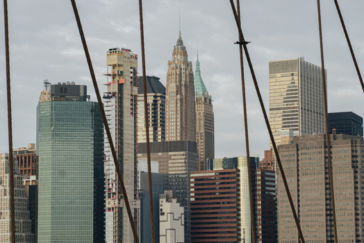 View of the New York City skyline featuring skyscrapers and the iconic suspension cables of the Brooklyn Bridge in the foreground New York New York United States.