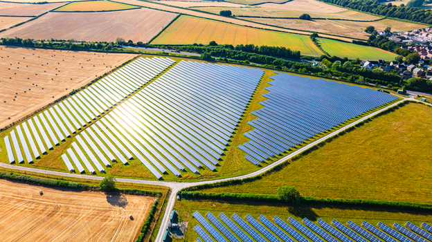 Aerial view of a large solar farm with rows of photovoltaic panels set in a rural landscape surrounded by agricultural fields and hedgerows in Dorset England United Kingdom. Aerial view of a large solar farm with rows of photovoltaic panels set in a rural landscape surrounded by agricultural fields and hedgerows in Dorset England United Kingdom.