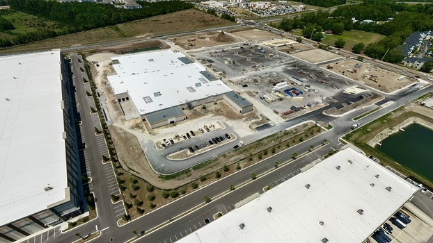 Aerial view of the industrial construction site at Foundry Lane featuring large white roofed warehouses and heavy machinery in World Golf Village Florida United States.