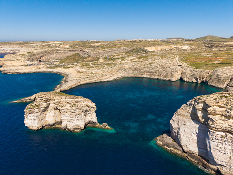 Aerial view of Dwejra Bay featuring the iconic Fungus Rock surrounded by turquoise Mediterranean waters and rugged limestone cliffs in Gozo Region Malta. Aerial view of Dwejra Bay featuring the iconic Fungus Rock surrounded by turquoise Mediterranean waters and rugged limestone cliffs in Gozo Region Malta.