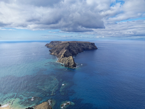 Aerial view of Ponta da Calheta a rocky peninsula extending into the deep blue Atlantic Ocean with clear turquoise waters surrounding the coastline Porto Santo Madeira Portugal. Aerial view of Ponta da Calheta a rocky peninsula extending into the deep blue Atlantic Ocean with clear turquoise waters surrounding the coastline Porto Santo Madeira Portugal.