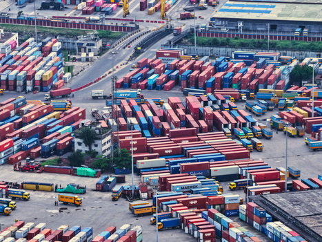 Aerial view of the busy Chattogram Port with rows of colorful shipping containers and trucks maneuvering through the industrial terminal in Chittagong Chittagong Division Bangladesh.