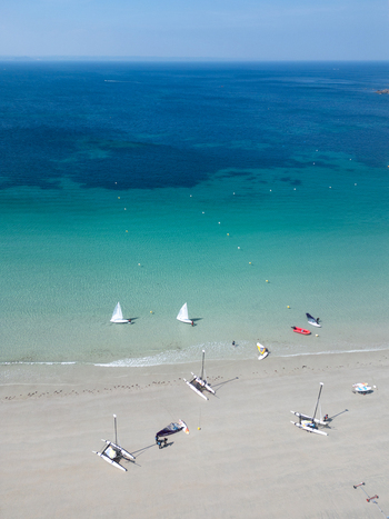 Aerial view of sailboats and catamarans on a sandy beach with turquoise water and a clear blue sky Trebeurden Brittany France. Aerial view of sailboats and catamarans on a sandy beach with turquoise water and a clear blue sky Trebeurden Brittany France.