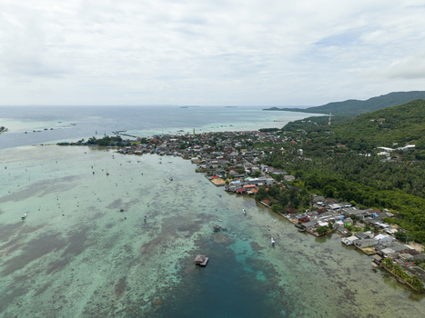 Aerial view of a vibrant coastal settlement where turquoise waters meet lush greenery creating a stunning contrast under the open sky Karimunjawa Central Java Indonesia. Aerial view of a vibrant coastal settlement where turquoise waters meet lush greenery creating a stunning contrast under the open sky Karimunjawa Central Java Indonesia.