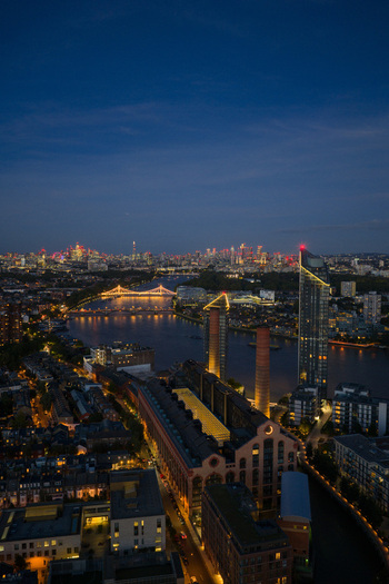 Aerial view of Lots Road Power Station and the River Thames with illuminated bridges and the city skyline at dusk in London England United Kingdom. Aerial view of Lots Road Power Station and the River Thames with illuminated bridges and the city skyline at dusk in London England United Kingdom.