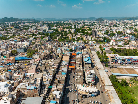 Aerial view of the dense urban landscape featuring traditional and modern buildings narrow streets and surrounding hills in Udaipur Rajasthan India.