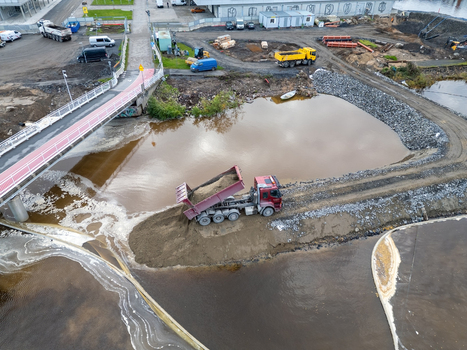Oulu Finland 18 September 2026 Aerial view of construction site at waterfront with a dump truck unloading soil near a bridge and water. Oulu Finland 18 September 2026 Aerial view of construction site at waterfront with a dump truck unloading soil near a bridge and water.