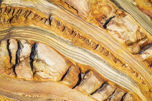 View of the intricate geological rock formations at Silence Beach with sedimentary layers and ochre mineral veins in Asturias Asturias Spain.