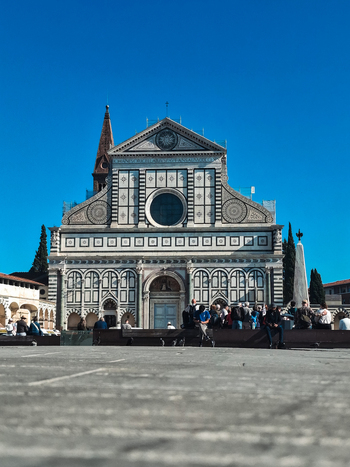 Florence Italy 26 April 2026 View of the Santa Maria Novella basilica with its intricate marble facade and geometric patterns under a clear blue sky with people gathered in the square. Florence Italy 26 April 2026 View of the Santa Maria Novella basilica with its intricate marble facade and geometric patterns under a clear blue sky with people gathered in the square.