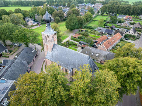 Aerial view of Nicolaaskerk surrounded by lush green trees and historic residential houses in Dwingeloo Drenthe Netherlands. Aerial view of Nicolaaskerk surrounded by lush green trees and historic residential houses in Dwingeloo Drenthe Netherlands.