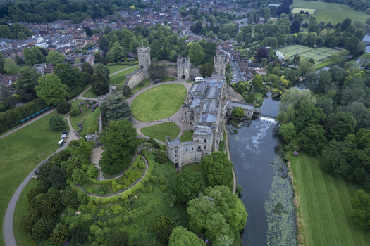 Aerial view of Warwick Castle surrounded by lush green gardens the River Avon and the historic town of Warwick England United Kingdom. Aerial view of Warwick Castle surrounded by lush green gardens the River Avon and the historic town of Warwick England United Kingdom.