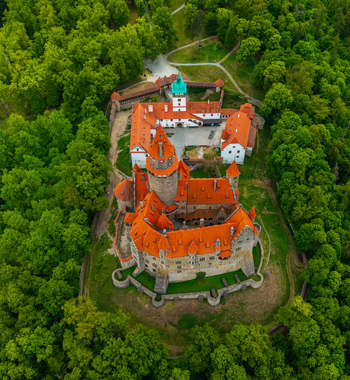 Aerial view of Bouzov Castle with its iconic red tiled roofs and tall stone tower nestled within a dense green forest in Bouzov Olomoucky kraj Czechia. Aerial view of Bouzov Castle with its iconic red tiled roofs and tall stone tower nestled within a dense green forest in Bouzov Olomoucky kraj Czechia.
