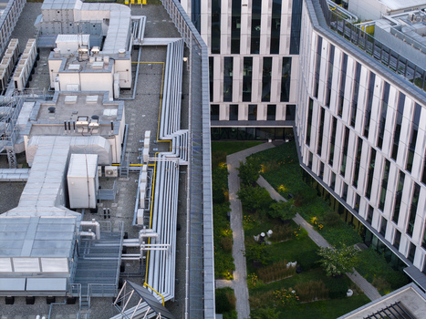 Aerial view of the modern HVAC cooling system and industrial pipes on the rooftop of an AI data center building with a green courtyard in Krakow Lesser Poland Voivode Poland.