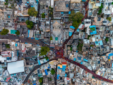 Aerial view of the historic Jagdish Temple surrounded by dense traditional rooftops narrow winding streets and a vibrant crowd of people in Udaipur Rajasthan India.