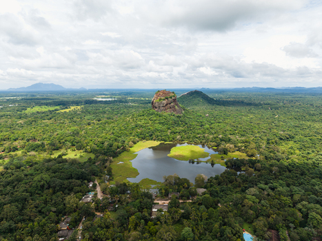 Aerial view of Sigiriya Lion Rock surrounded by lush tropical jungle and a serene lake under a cloudy sky Sigiriya Central Province Sri Lanka. Aerial view of Sigiriya Lion Rock surrounded by lush tropical jungle and a serene lake under a cloudy sky Sigiriya Central Province Sri Lanka.