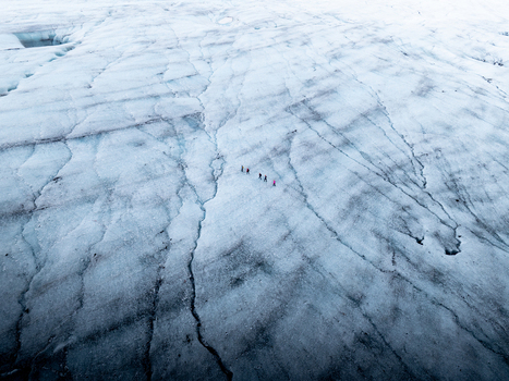 Aerial view of Breidamerkurjokull glacier with a small group of hikers trekking across the vast icy surface in Sveitarfelagid Hornaf Iceland. Aerial view of Breidamerkurjokull glacier with a small group of hikers trekking across the vast icy surface in Sveitarfelagid Hornaf Iceland.