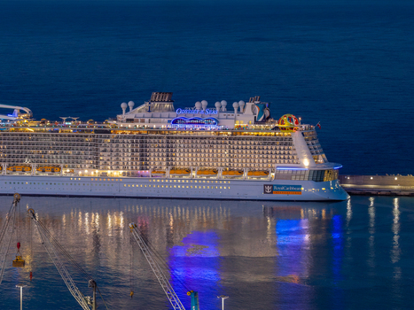 Civitavecchia Italy 23 August 2026 Aerial view of the Odyssey of the Seas cruise ship docked at Civitavecchia Port with illuminated decks reflecting on the water and port cranes.