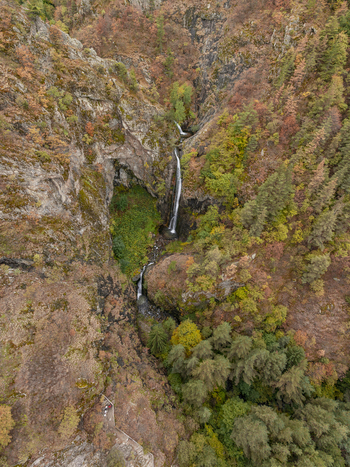 Aerial view of the Ovcharenski Waterfall Goritsa cascading down rocky cliffs surrounded by vibrant autumn forest and dense woodland in Ovchartsi Kyustendil Province Bulgaria. Aerial view of the Ovcharenski Waterfall Goritsa cascading down rocky cliffs surrounded by vibrant autumn forest and dense woodland in Ovchartsi Kyustendil Province Bulgaria.