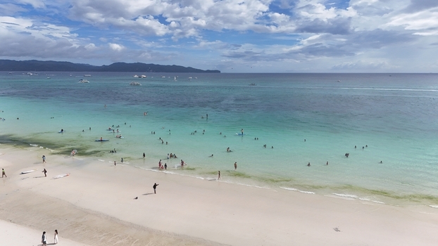 Malay Philippines 02 May 2026 Aerial view of Boracay Island with people swimming in turquoise waters and white sand beach under a cloudy sky.