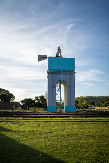 View of the historic water tower with a windmill mechanism painted in light blue and purple standing in a grassy field in Guaviravi Corrientes Province Argentina.