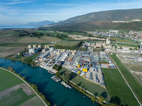 Aerial view of the Cressier Refinery industrial complex situated along a canal with barges surrounded by agricultural fields and mountains in Cornaux Neuchatel Switzerland. Aerial view of the Cressier Refinery industrial complex situated along a canal with barges surrounded by agricultural fields and mountains in Cornaux Neuchatel Switzerland.