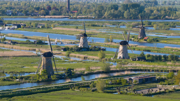 Aerial view of the historic Kinderdijk windmills standing along winding canals amidst lush green fields Kinderdijk South Holland Netherlands. Aerial view of the historic Kinderdijk windmills standing along winding canals amidst lush green fields Kinderdijk South Holland Netherlands.