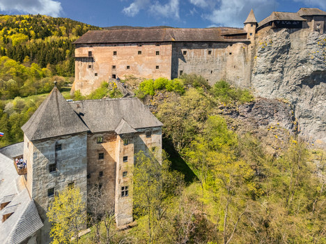 Aerial view of Orava Castle perched on a high rock cliff surrounded by lush green forests and rolling hills under a blue sky in Dolny Kubin Zilinsky kraj Slovakia. Aerial view of Orava Castle perched on a high rock cliff surrounded by lush green forests and rolling hills under a blue sky in Dolny Kubin Zilinsky kraj Slovakia.