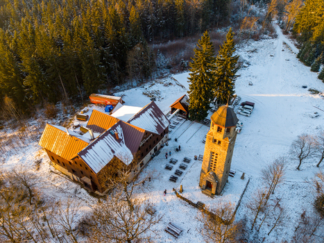 Aerial view of Bramberk observation tower and adjacent mountain hut surrounded by snowy forest landscape during golden hour in Lucany nad Nisou Liberec Region Czechia. Aerial view of Bramberk observation tower and adjacent mountain hut surrounded by snowy forest landscape during golden hour in Lucany nad Nisou Liberec Region Czechia.