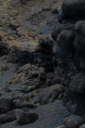 View of stark black volcanic rock formations rise against a backdrop of dark textured earth creating a rugged otherworldly landscape Skaftárhreppur Skaftárhreppur Iceland. View of stark black volcanic rock formations rise against a backdrop of dark textured earth creating a rugged otherworldly landscape Skaftárhreppur Skaftárhreppur Iceland.