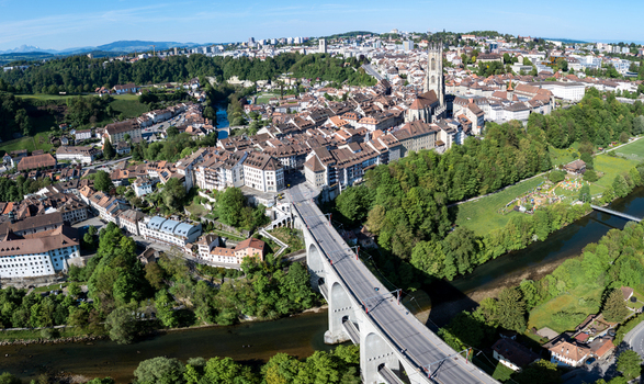 Aerial view of St Nicolas Cathedral and the Zaehringen Bridge spanning the Sarine river amidst the historic old town rooftops and lush greenery in Fribourg Fribourg Switzerland. Aerial view of St Nicolas Cathedral and the Zaehringen Bridge spanning the Sarine river amidst the historic old town rooftops and lush greenery in Fribourg Fribourg Switzerland.