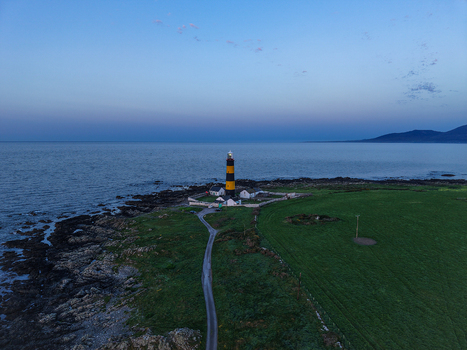 Aerial view of St. John s Point Lighthouse with its distinctive black and yellow stripes situated on the rocky coastline near green fields in Newcastle Northern Ireland United Kingdom. Aerial view of St. John s Point Lighthouse with its distinctive black and yellow stripes situated on the rocky coastline near green fields in Newcastle Northern Ireland United Kingdom.