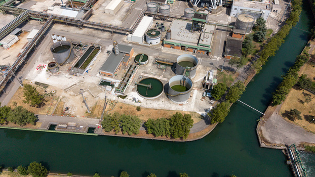 Aerial view of a modern combined cycle natural gas power station with industrial tanks cooling infrastructure and piping along a canal in Tavazzano con Villavesco Lombardy Italy.